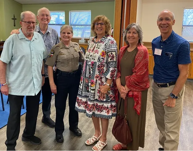 Advocates for Social Justice Reform team members smiling together with a police officer.
